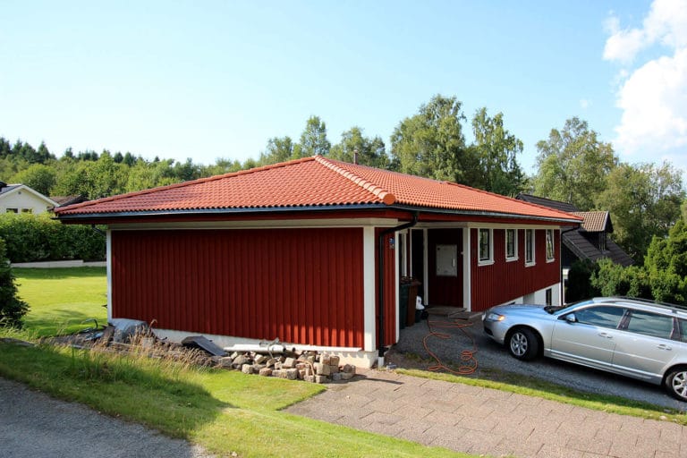 Bilderna visar ett rött envåningshus med tegeltak och en grå kombi parkerad på uppfarten. Huset är omgivet av gräs och träd och vid ingången står en orange slang som är upprullad.